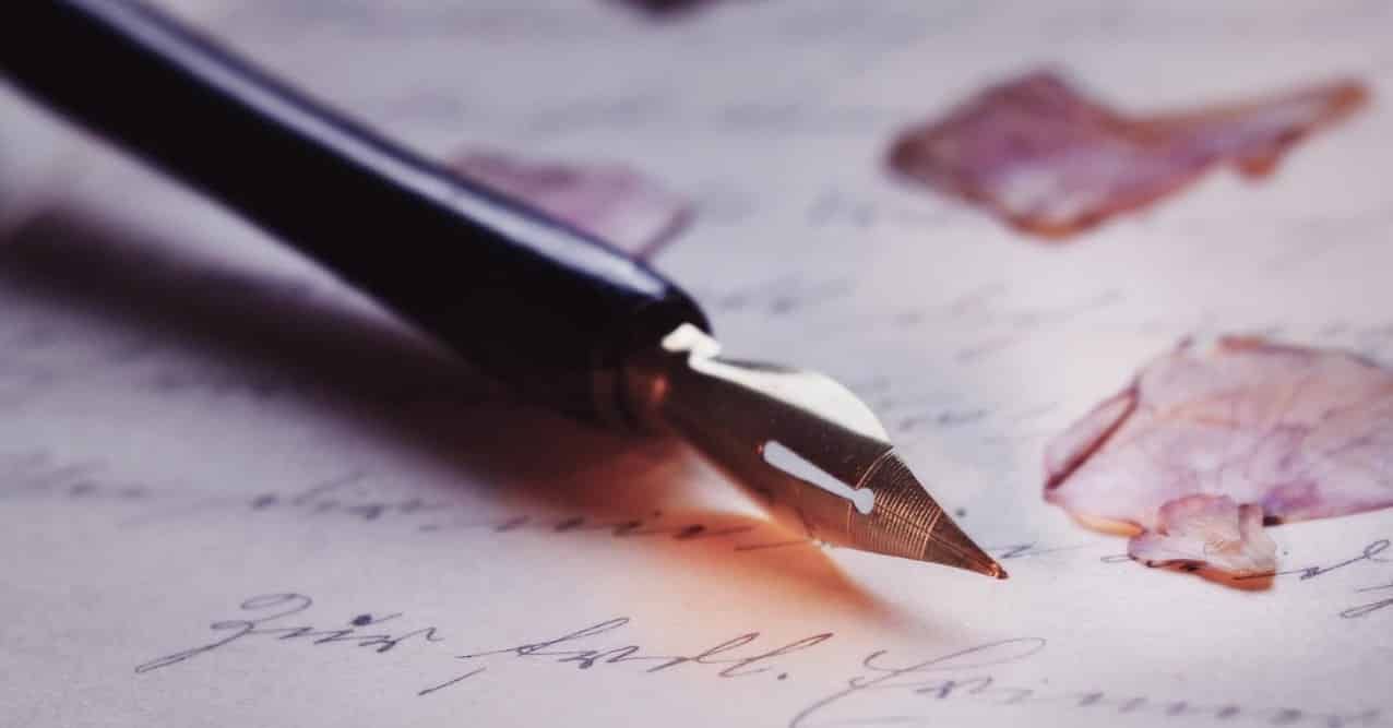 A vintage fountain pen rests on a handwritten letter adorned with delicate pink flower petals