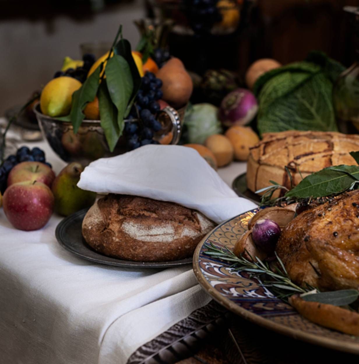 A lavish feast display with colorful fruits, freshly baked bread, and a beautifully garnished roasted dish